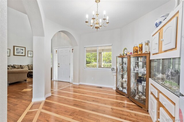 17391 E Weaver Ave, Aurora, CO 80016 - foyer entrance featuring light wood finished floors, arched walkways, a chandelier, and baseboards