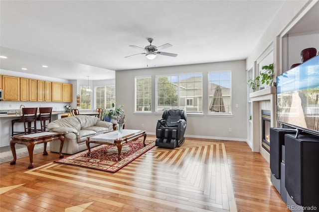 17391 E Weaver Ave, Aurora, CO 80016 - living area featuring recessed lighting, light wood-style flooring, a glass covered fireplace, a ceiling fan, and baseboards