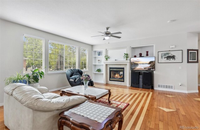 17391 E Weaver Ave, Aurora, CO 80016 - living room with a glass covered fireplace, ceiling fan, light wood-type flooring, and baseboards