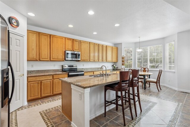 17391 E Weaver Ave, Aurora, CO 80016 - kitchen featuring stainless steel appliances, inlaid floor details, recessed lighting, a sink, and an island with sink