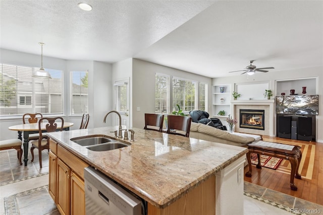 17391 E Weaver Ave, Aurora, CO 80016 - kitchen with dishwasher, a sink, ceiling fan, a glass covered fireplace, and an island with sink