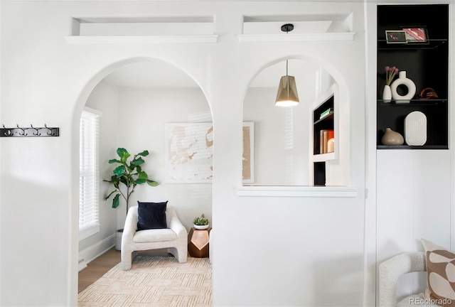 sitting room with arched walkways and wood finished floors