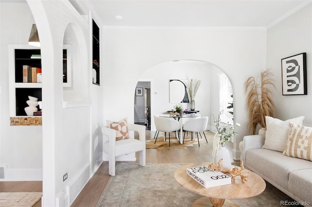 living area with visible vents, arched walkways, crown molding, and wood finished floors