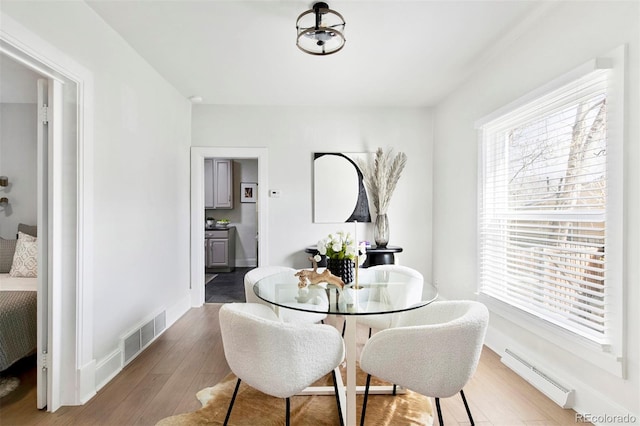 dining area with visible vents, a baseboard radiator, baseboards, and wood finished floors