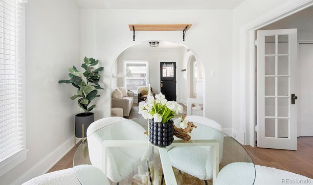 dining area with arched walkways and wood finished floors