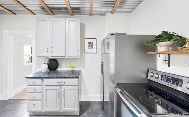 kitchen with beam ceiling, baseboards, white cabinets, stainless steel electric stove, and dark stone counters