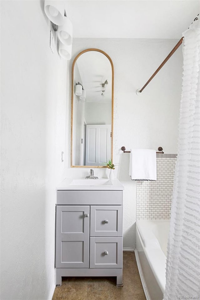 bathroom featuring baseboards, shower / bath combo with shower curtain, and vanity