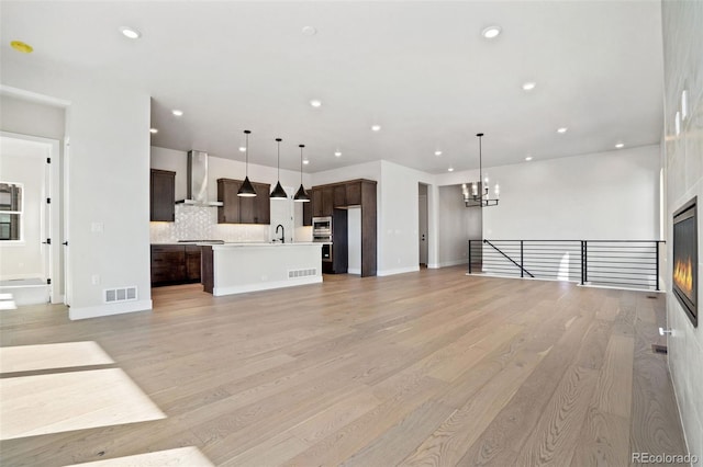 unfurnished living room featuring a notable chandelier, sink, and light hardwood / wood-style floors