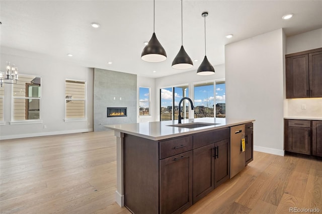 kitchen featuring a center island with sink, decorative light fixtures, light hardwood / wood-style flooring, a tile fireplace, and sink