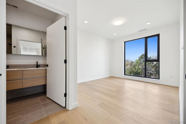 spare room with light hardwood / wood-style floors and sink