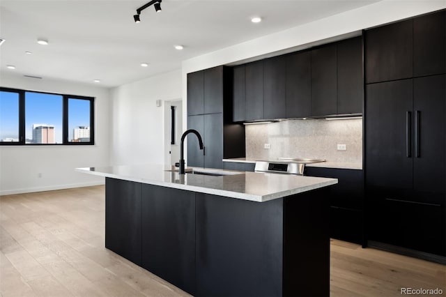 kitchen featuring sink, a spacious island, electric stove, decorative backsplash, and light hardwood / wood-style flooring