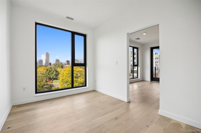 unfurnished room featuring light wood-style floors, baseboards, and visible vents