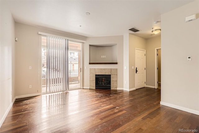 unfurnished living room featuring a fireplace, wood finished floors, visible vents, and baseboards