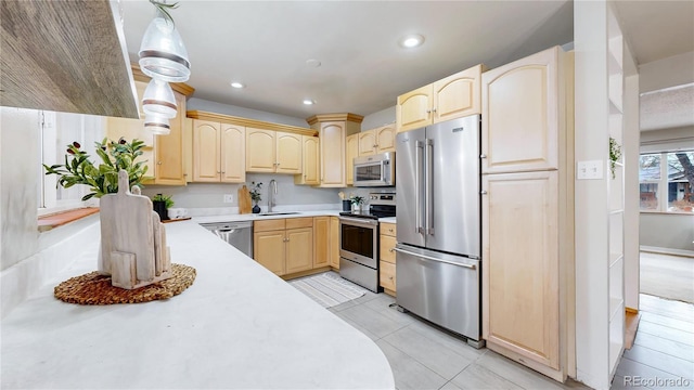 kitchen with appliances with stainless steel finishes, light brown cabinetry, decorative light fixtures, sink, and light tile patterned floors