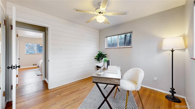 office featuring ceiling fan, a wealth of natural light, wood walls, and light wood-type flooring