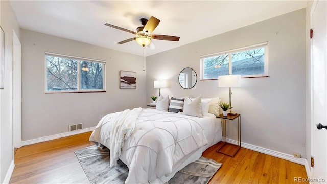 bedroom with multiple windows, ceiling fan, and light hardwood / wood-style floors