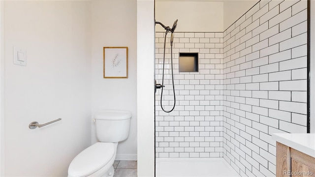 bathroom with vanity, tiled shower, and toilet