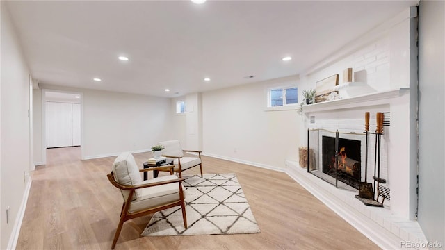 sitting room featuring a brick fireplace and light hardwood / wood-style floors