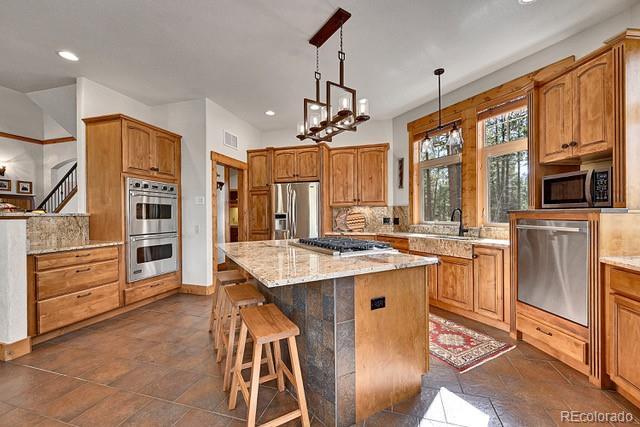 15947 Huckleberry Hts, Colorado Springs, CO 80908 - kitchen featuring light stone countertops, a breakfast bar area, stainless steel appliances, recessed lighting, and visible vents