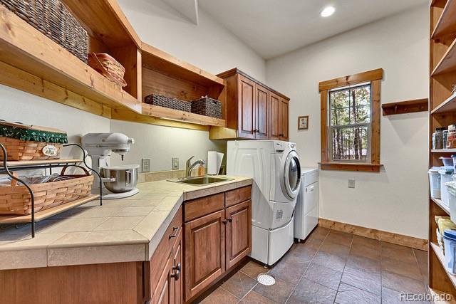 15947 Huckleberry Hts, Colorado Springs, CO 80908 - washroom featuring baseboards, recessed lighting, separate washer and dryer, a sink, and cabinet space