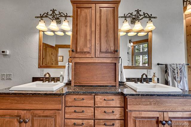 15947 Huckleberry Hts, Colorado Springs, CO 80908 - full bath with a sink, a textured wall, and double vanity