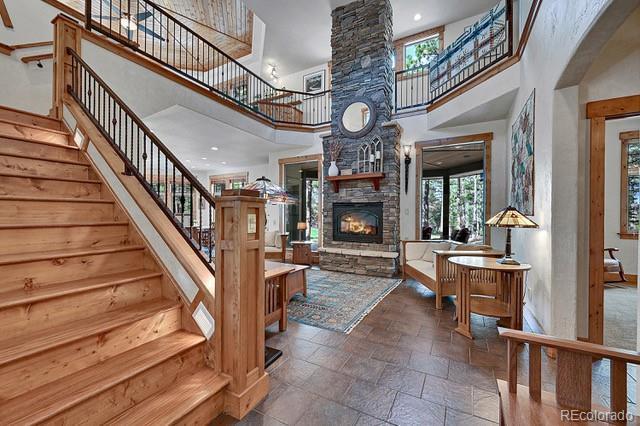 15947 Huckleberry Hts, Colorado Springs, CO 80908 - interior space featuring a stone fireplace, stone tile floors, stairs, and a high ceiling