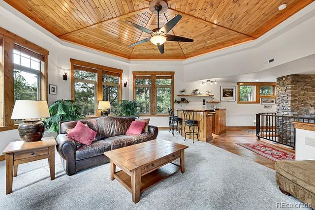 15947 Huckleberry Hts, Colorado Springs, CO 80908 - living area featuring a ceiling fan, a healthy amount of sunlight, wood ceiling, and a raised ceiling