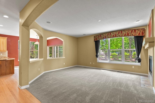 6533 S Ouray St, Aurora, CO 80016 - unfurnished room featuring recessed lighting, baseboards, a fireplace with flush hearth, light carpet, and light wood finished floors