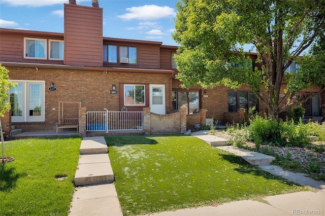 435 Dahlia St, Fort Morgan, CO 80701 - view of front of house with a chimney, brick siding, and a front lawn