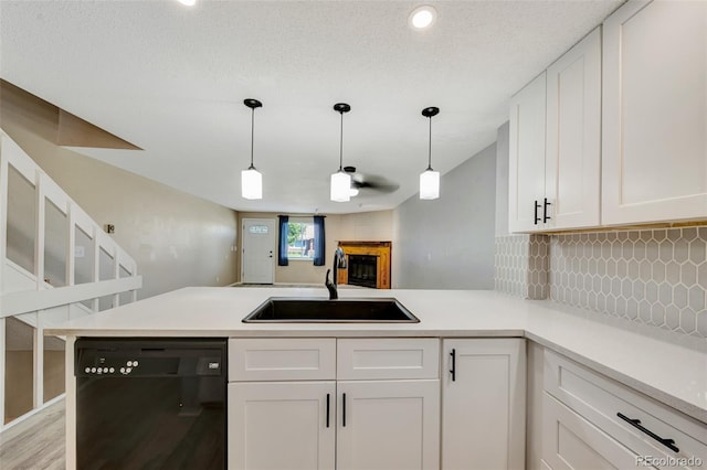 435 Dahlia St, Fort Morgan, CO 80701 - kitchen featuring black dishwasher, a peninsula, white cabinetry, backsplash, and a fireplace