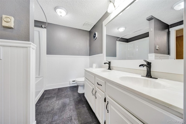435 Dahlia St, Fort Morgan, CO 80701 - bathroom with wainscoting, double vanity, a textured ceiling, bathtub / shower combination, and a baseboard radiator
