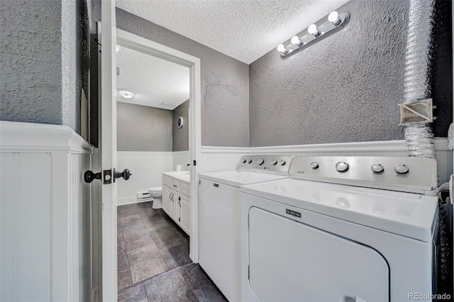 435 Dahlia St, Fort Morgan, CO 80701 - washroom featuring a textured ceiling, washer and dryer, a textured wall, wainscoting, and dark tile patterned flooring