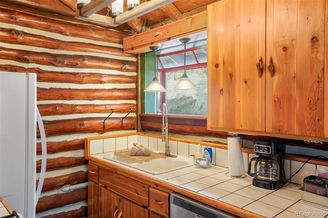 kitchen with white refrigerator, decorative light fixtures, sink, tile countertops, and log walls