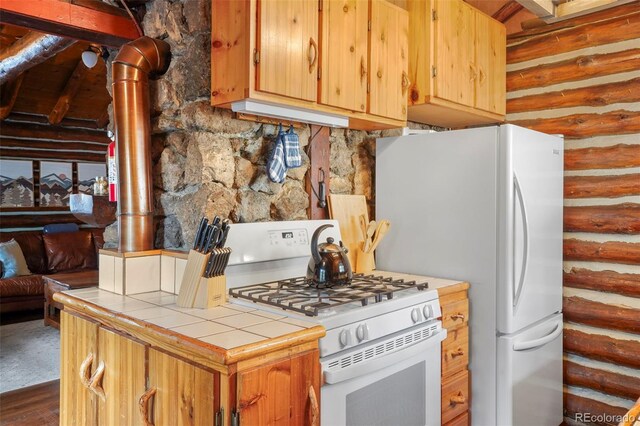 kitchen featuring white appliances, tile countertops, log walls, and dark hardwood / wood-style flooring