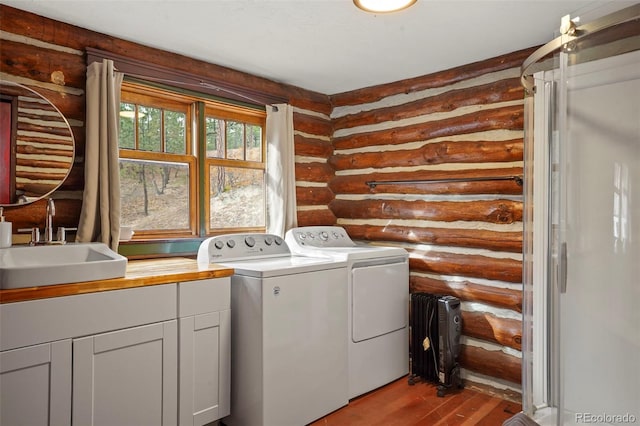 laundry room with cabinets, sink, log walls, light hardwood / wood-style flooring, and washing machine and clothes dryer