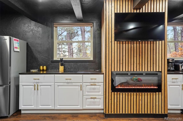 kitchen with white cabinets, stainless steel fridge, beamed ceiling, and dark wood-type flooring