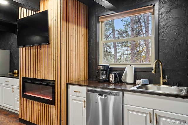 kitchen with stainless steel dishwasher, white cabinetry, and sink