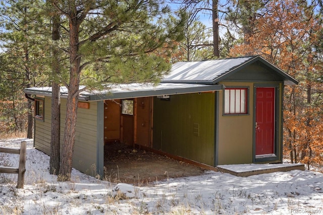 snow covered structure with a carport