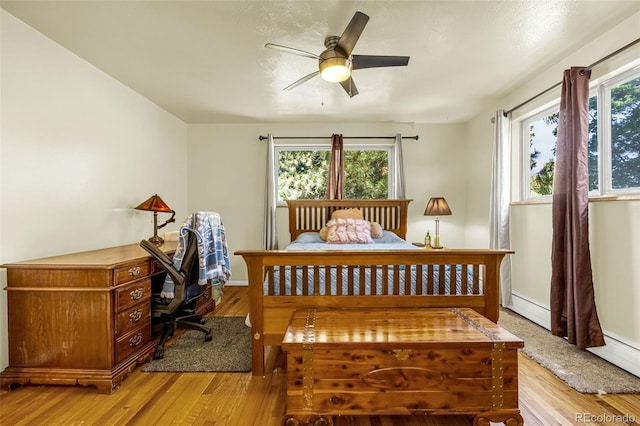 12475 W 38th Ave, Wheat Ridge, CO 80033 - bedroom featuring multiple windows, light wood-style flooring, and a baseboard heating unit