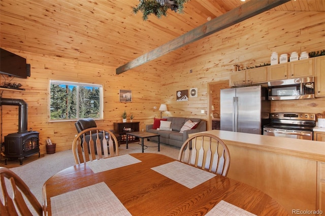526 Wakanda Trl, Woodland Park, CO 80863 - dining space with carpet floors, a wood stove, wood walls, and vaulted ceiling with beams