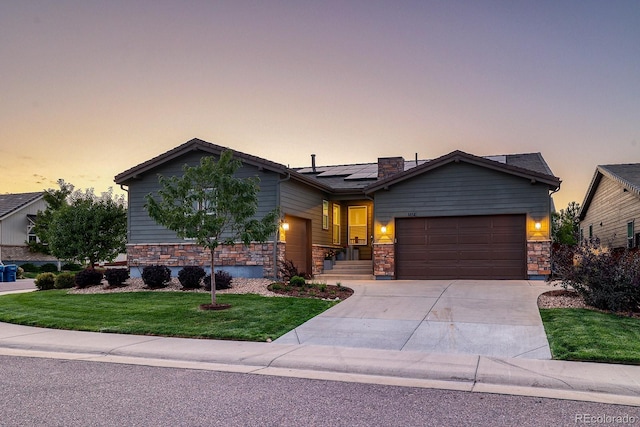 view of front of house with a lawn, solar panels, and a garage