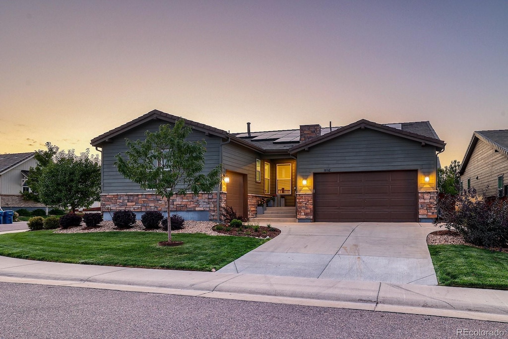 view of front of home featuring solar panels, a lawn, and a garage