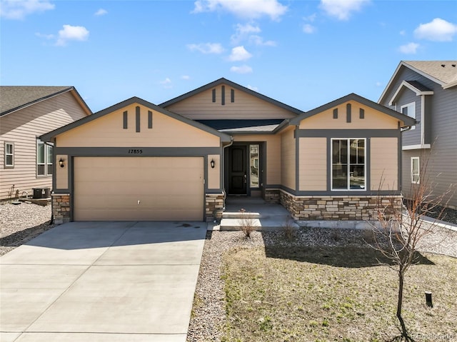 view of front facade featuring cooling unit, driveway, stone siding, and an attached garage