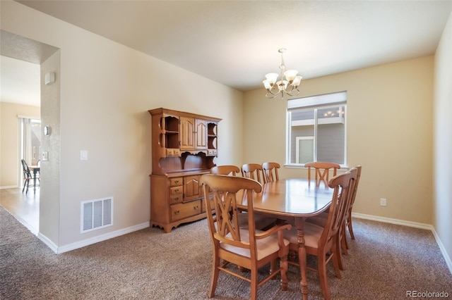dining area with light carpet, an inviting chandelier, baseboards, and visible vents