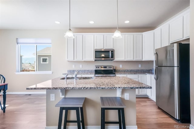 kitchen with a sink, light wood-style flooring, appliances with stainless steel finishes, and white cabinetry