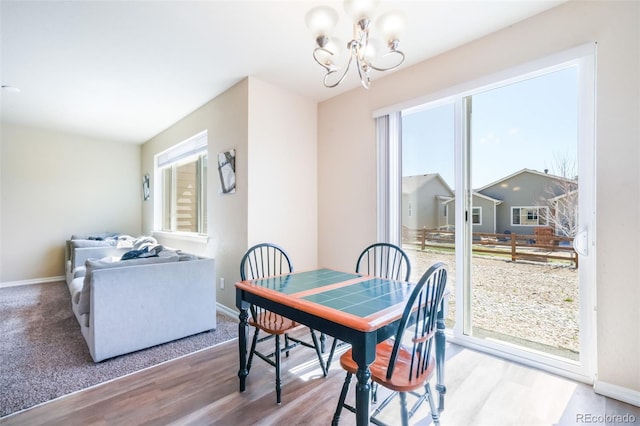 dining area featuring baseboards, a chandelier, wood finished floors, and a healthy amount of sunlight