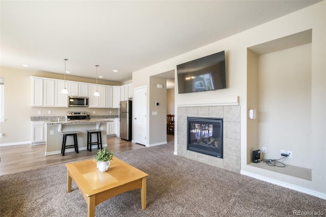 living area featuring recessed lighting, carpet flooring, a fireplace, and baseboards