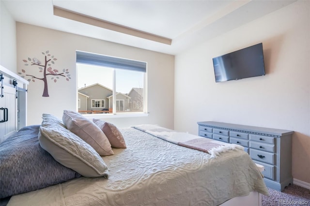 carpeted bedroom featuring a tray ceiling, baseboards, and a barn door