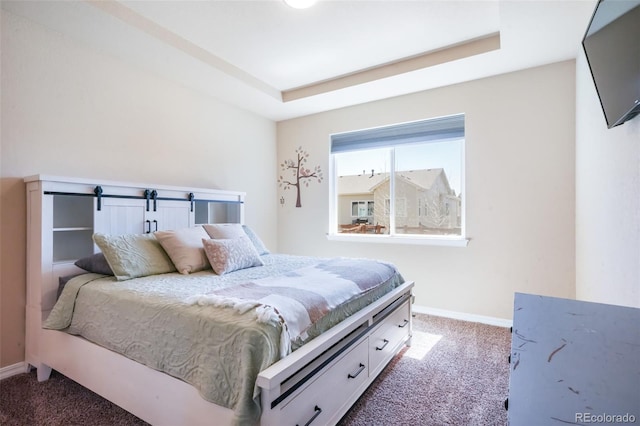 carpeted bedroom with a tray ceiling and baseboards
