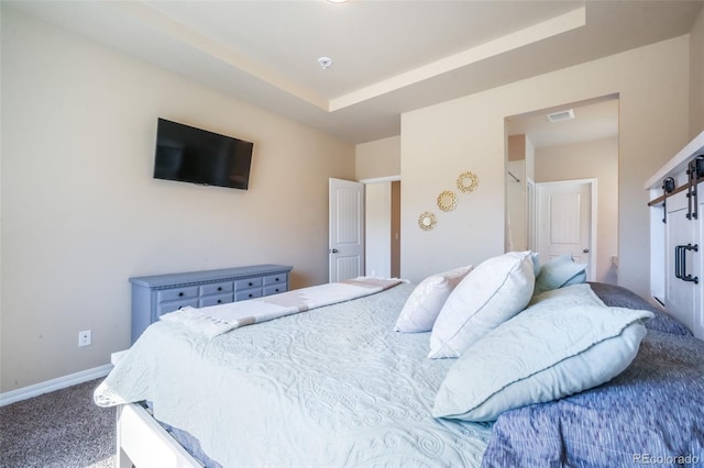 bedroom featuring visible vents, a barn door, carpet flooring, a raised ceiling, and baseboards